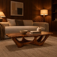 Rectangular coffee table with a slab top and branching arched base in an evening living room with walnut wall paneling