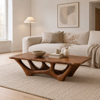 Rectangular coffee table with a slab top and branching arched base in a Scandinavian living room with white walls