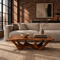 Rectangular coffee table with a slab top and branching arched base in an industrial loft living room with exposed brick