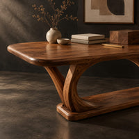 Corner detail of rectangular desk on arched loop legs joined by a flat wood base beside wood, brass and linen samples