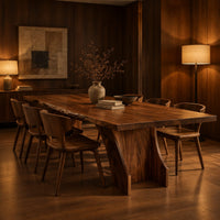 Rectangular dining table with a thick slab top on a wide hourglass pedestal in an evening dining room with walnut wall paneling