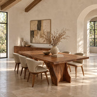 Rectangular dining table with a thick slab top on a wide hourglass pedestal in a bright open plan dining room