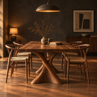 Rectangular dining table on two hourglass pedestal legs in a dark dining room at golden hour