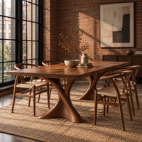 Rectangular dining table on two hourglass pedestal legs in an industrial loft dining room with exposed brick