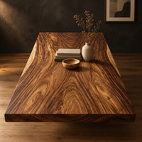 Rectangular wood table top slab with bold swirling grain and a thick edge in a dark studio against a charcoal plaster wall