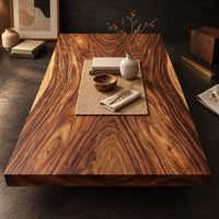 Corner detail of rectangular wood table top slab with bold swirling grain and a thick edge beside wood, brass and linen samples