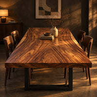Rectangular wood table top slab with bold swirling grain and a thick edge in a dark dining room at golden hour