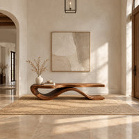 Low bench with a long slab seat on a flowing ribbon shaped base in a bright open plan entryway