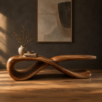 Low ribbon bench with a looping base and a long flat top in a dark studio against a charcoal plaster wall