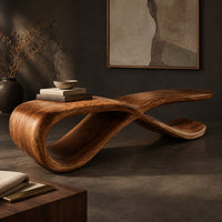 Corner detail of low ribbon bench with a looping base and a long flat top beside wood, brass and linen samples
