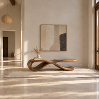 Low ribbon bench with a looping base and a long flat top in a bright open plan entryway