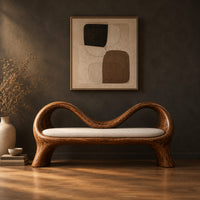 Bench with a wave shaped ribbon frame and a slim pale seat pad in a dark studio against a charcoal plaster wall