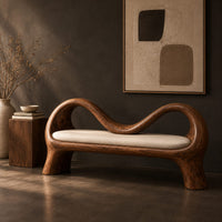 Corner detail of bench with a wave shaped ribbon frame and a slim pale seat pad beside wood, brass and linen samples