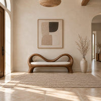 Bench with a wave shaped ribbon frame and a slim pale seat pad in a bright open plan entryway