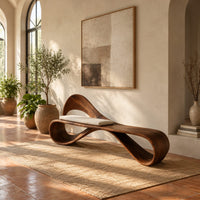 Ribbon loop bench with an arched backrest and a cream cushion in a bright entryway with arched windows and plants
