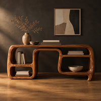 Console table with looping ribbon sides and open cubbies on both ends in a dark studio against a charcoal plaster wall