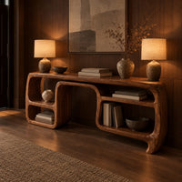Console table with looping ribbon sides and open cubbies on both ends in an evening entryway with walnut wall paneling