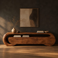 Wooden tv stand with a looping ribbon band and wave carved front panels in a dark studio against a charcoal plaster wall