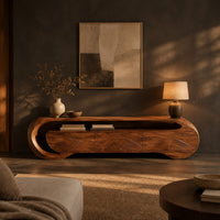 Wooden tv stand with a looping ribbon band and wave carved front panels in a dark living room at golden hour