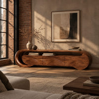 Wooden tv stand with a looping ribbon band and wave carved front panels in an industrial loft living room with exposed brick