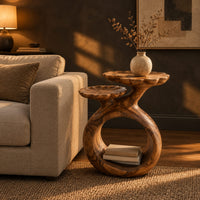 Side table with a looped ring base and two scalloped dish tops in a dark living room at golden hour