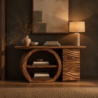 Console table with a large circular open shelf frame beside a wave carved cabinet in a dark entryway at golden hour