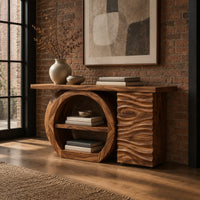 Console table with a large circular open shelf frame beside a wave carved cabinet in an industrial loft entryway with exposed brick
