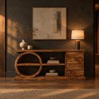 Console table with a circular shelf frame, four stacked panels and a plinth in a dark entryway at golden hour