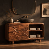 Bathroom vanity with ripple carved doors, open shelves and short tapered feet, three-quarter view showing the grain