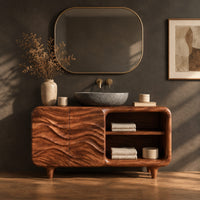 Corner detail of bathroom vanity with ripple carved doors, open shelves and short tapered feet beside wood, brass and linen samples