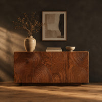 Four door sideboard carved with concentric ripple rings on a plinth base in a dark studio against a charcoal plaster wall