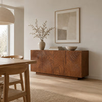 Four door sideboard carved with concentric ripple rings on a plinth base in a Scandinavian dining room with white walls