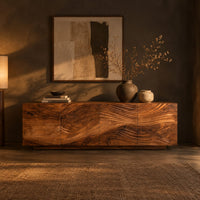 Low sideboard with four carved wave panels on a recessed plinth base in a dark dining room at golden hour