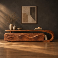 Low tv stand with ripple carved panels and a looped sweeping end in a dark studio against a charcoal plaster wall