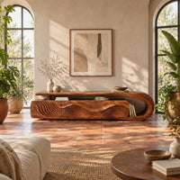 Low tv stand with ripple carved panels and a looped sweeping end in a bright living room with arched windows and plants