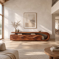 Low tv stand with ripple carved panels and a looped sweeping end in a bright open plan living room