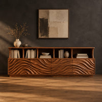 Tv stand with ripple carved front panels and four open display shelves in a dark studio against a charcoal plaster wall