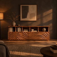 Tv stand with ripple carved front panels and four open display shelves in a dark living room at golden hour