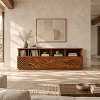 Tv stand with ripple carved front panels and four open display shelves in a bright open plan living room