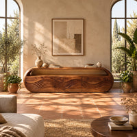 Capsule shaped tv stand with three wave carved front panels in a bright living room with arched windows and plants