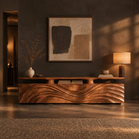 Low wooden tv stand with wave carved doors and a raised top shelf in a dark living room at golden hour