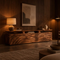 Low wooden tv stand with wave carved doors and a raised top shelf in an evening living room with walnut wall paneling