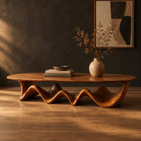Long coffee table with a freeform oval top on a rippling wave shaped base in a dark studio against a charcoal plaster wall