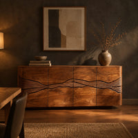 Sideboard with a winding carved band across warm grain front panels in a dark dining room at golden hour