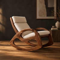 Rocking chair with looped side frames, curved runners and long cushions in a dark studio against a charcoal plaster wall