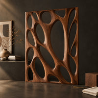 Corner detail of tall wooden room divider panel with branching ribs and large oval openings beside wood, brass and linen samples