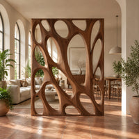 Tall wooden room divider panel with branching ribs and large oval openings in a bright open-plan living room with arched windows and plants