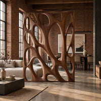 Tall wooden room divider panel with branching ribs and large oval openings in an industrial loft open-plan living room with exposed brick