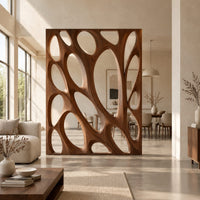 Tall wooden room divider panel with branching ribs and large oval openings in a bright open plan open-plan living room