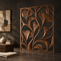 Corner detail of openwork room divider with carved fan shaped leaves in a slim frame beside wood, brass and linen samples
